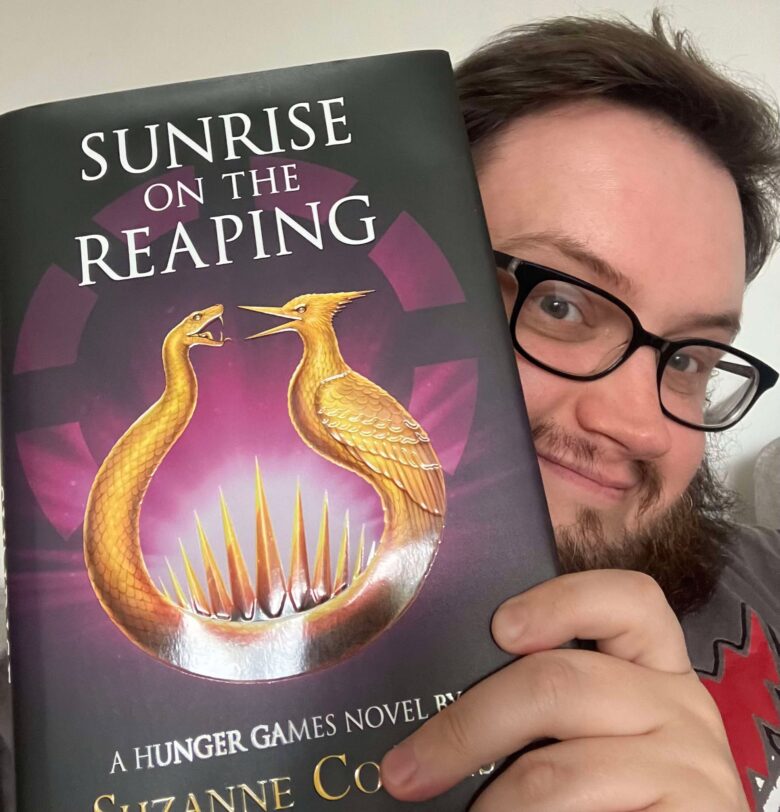 Daniel Cause holding Sunrise on the Reaping by Suzanne Collins